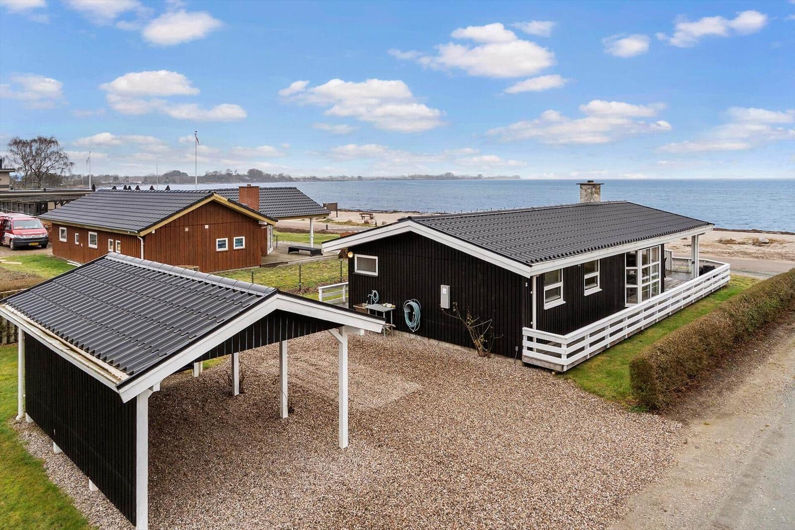 Schwarzes Holzhaus mit weißem Geländer und Terrasse direkt am Wasser.