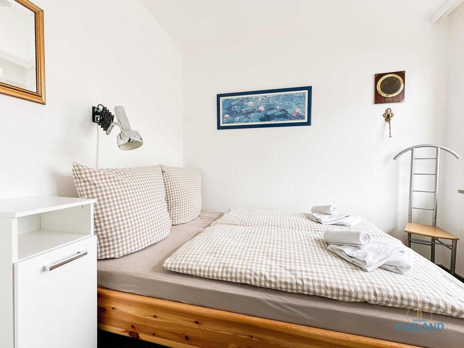 Schlafzimmer mit Bett, Nachttisch und Wandbild.