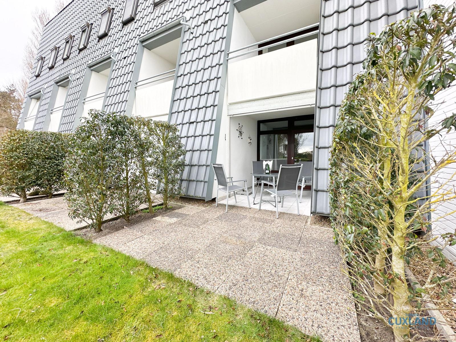 Terrasse mit Tisch und Stühlen vor modernem Haus mit Balkon.