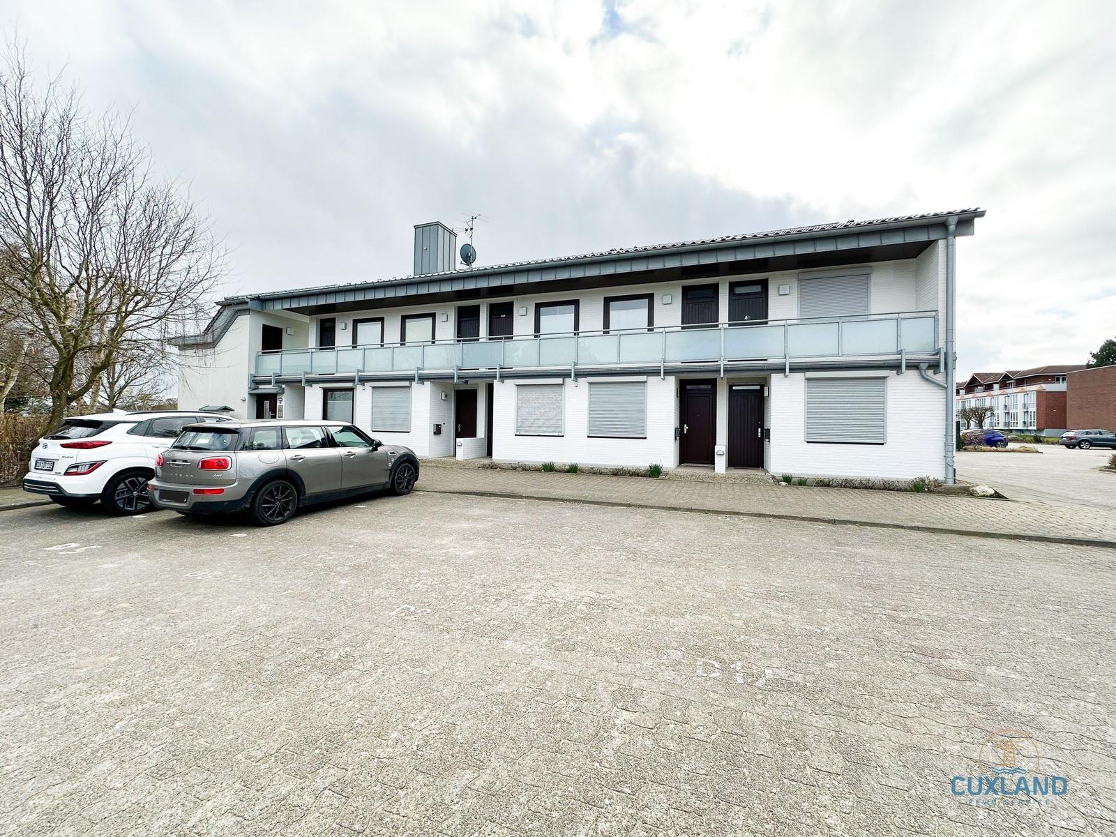 Zwei-Stöckiges Haus mit Balkon und Parkplätzen vorne.