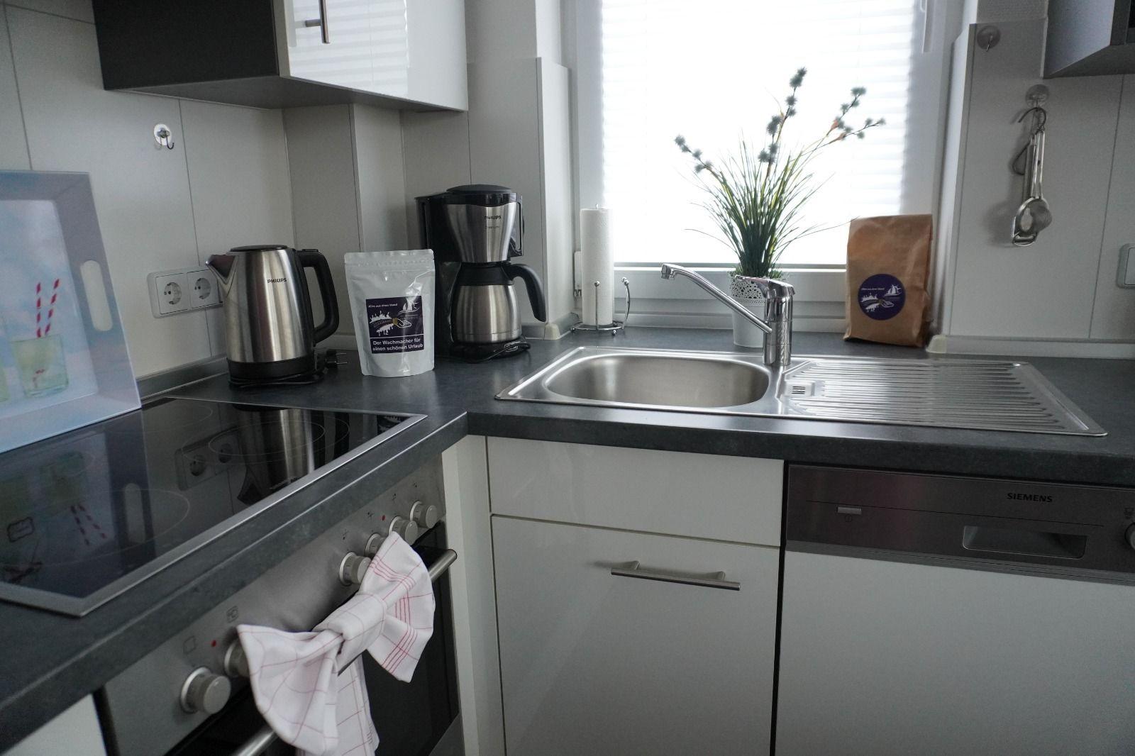 Küche mit Spüle, Kaffeemaschine und Kochfeld.