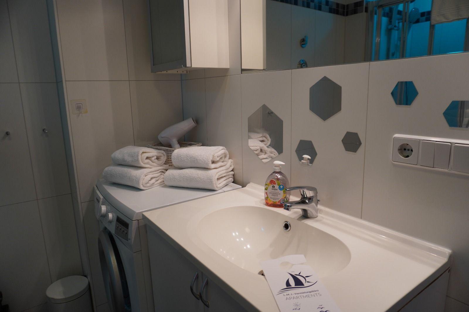 Badezimmer mit Waschmaschine, Spiegel und Handtüchern