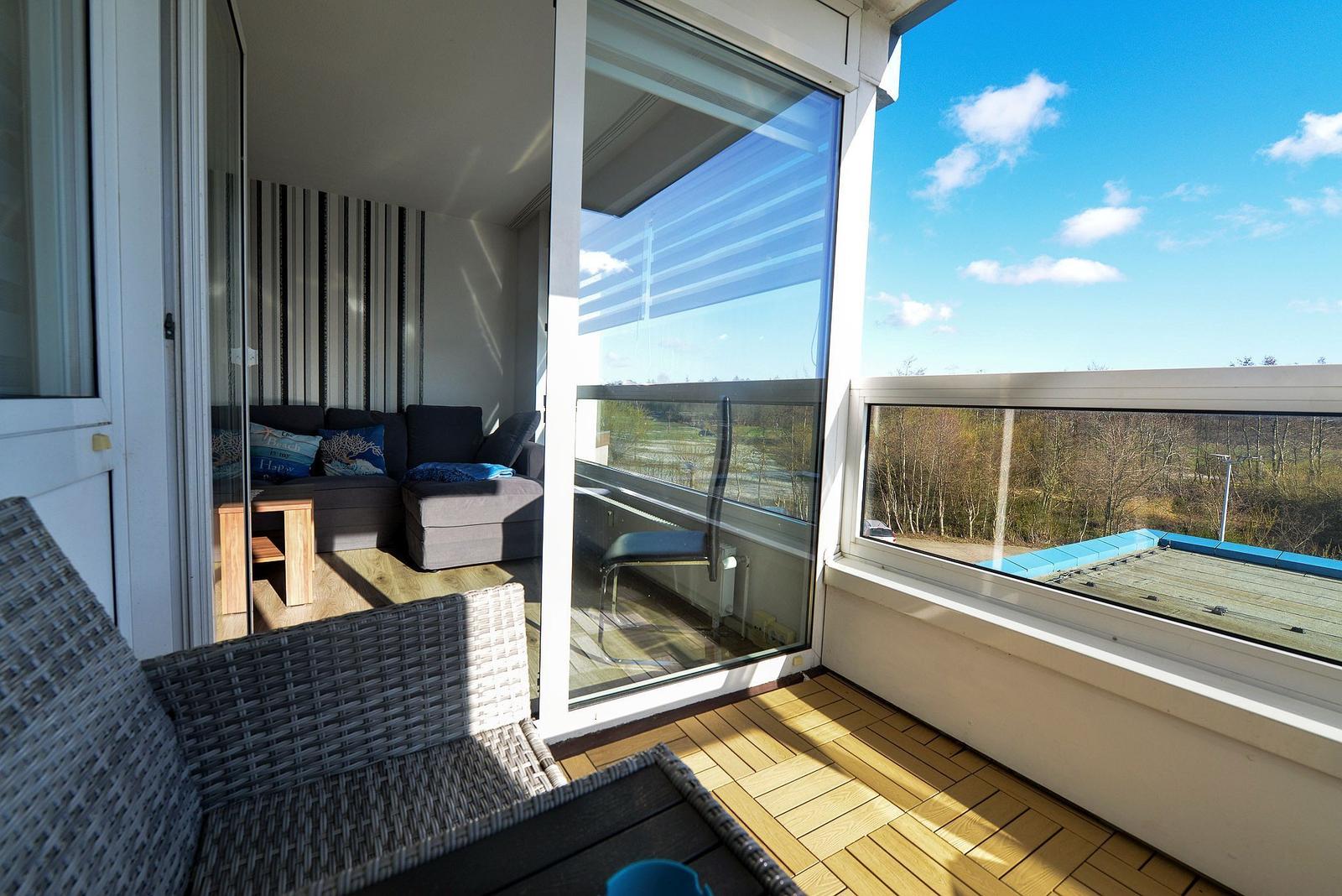 Terrasse mit Sitzgelegenheit und Blick auf Wald und Himmel.