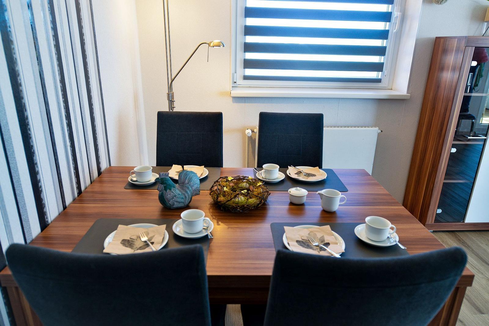 Esszimmer mit vier Stühlen, Tisch gedeckt, Fenster mit Jalousie.