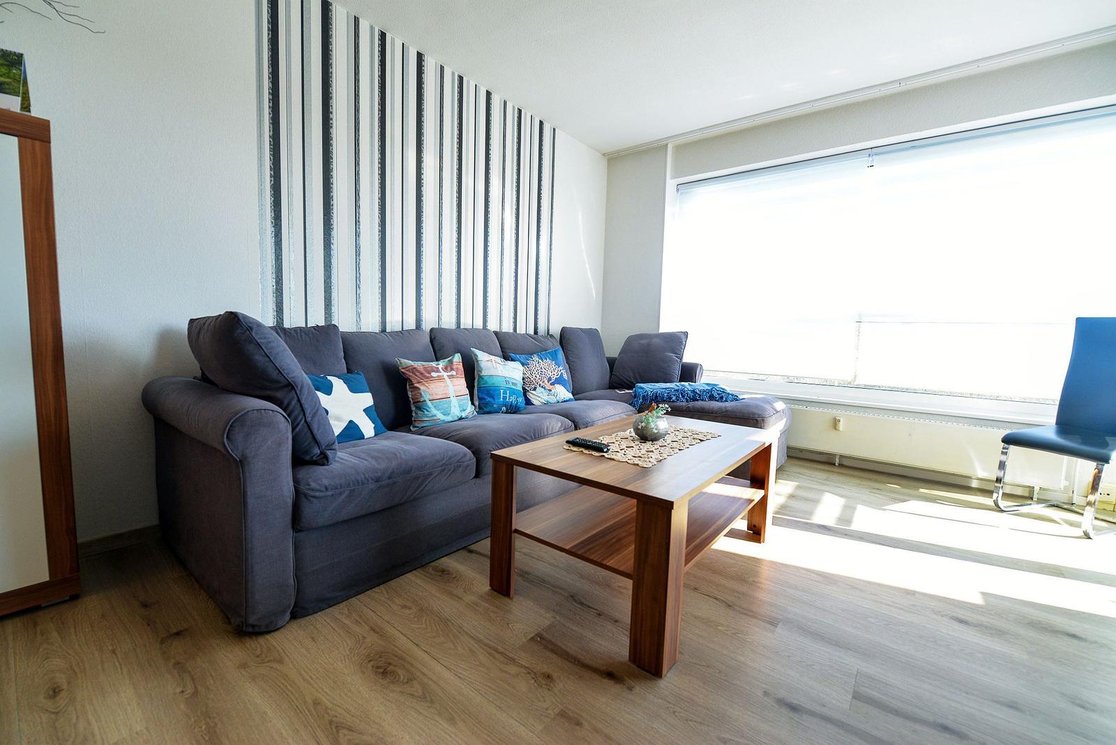 Wohnzimmer mit Sofa, Couchtisch und großem Fenster