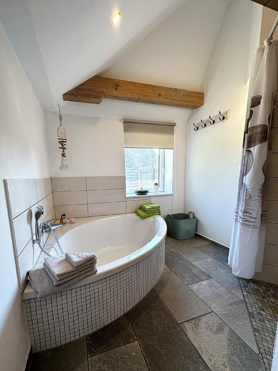 Bad mit Badewanne, Fenster und Holzbalken an der Decke.