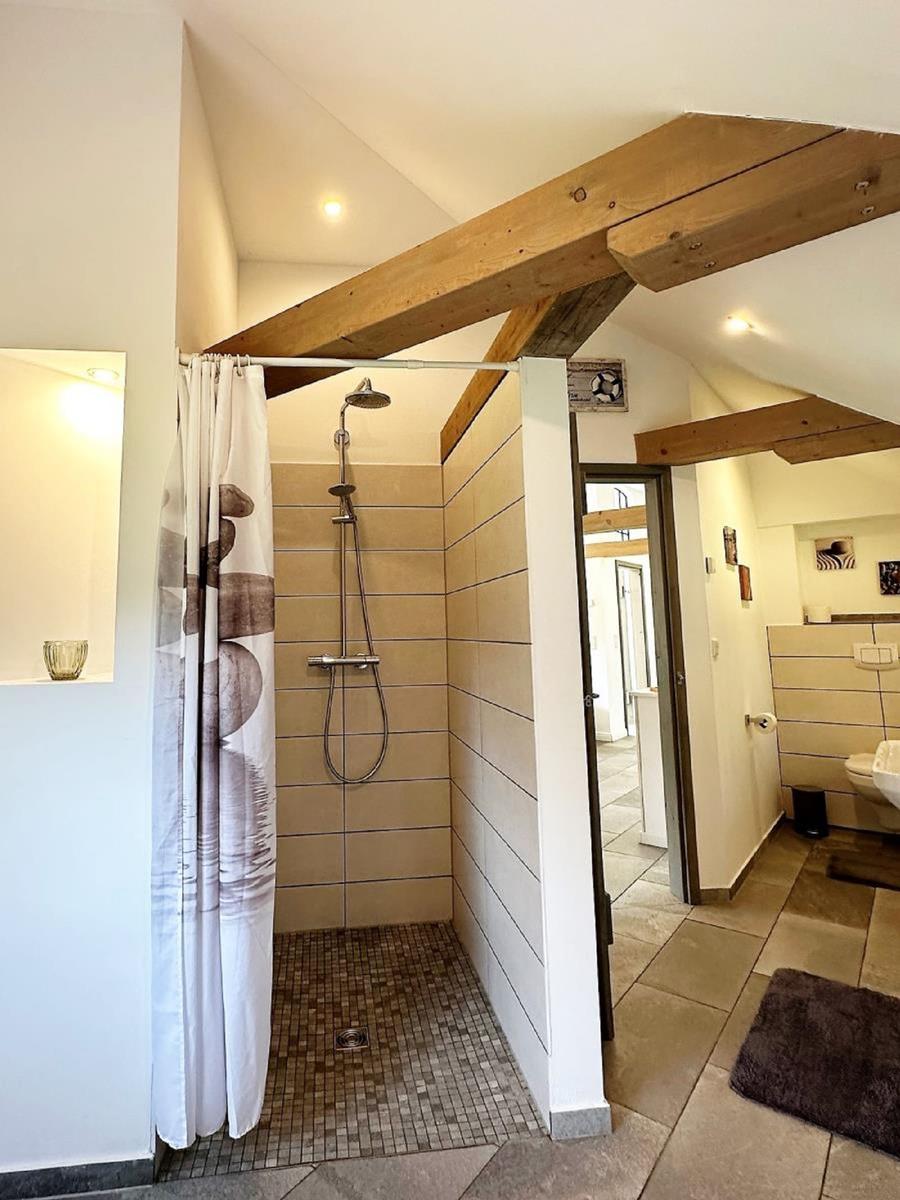 Dusche mit Duschvorhang und Holzbalken an der Decke.