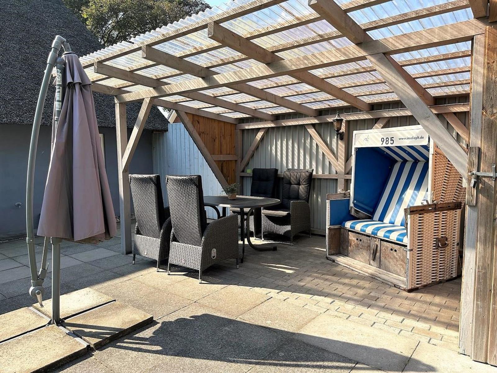 Terrasse mit Pavillon, Tisch, Stühlen und Strandkorb.
