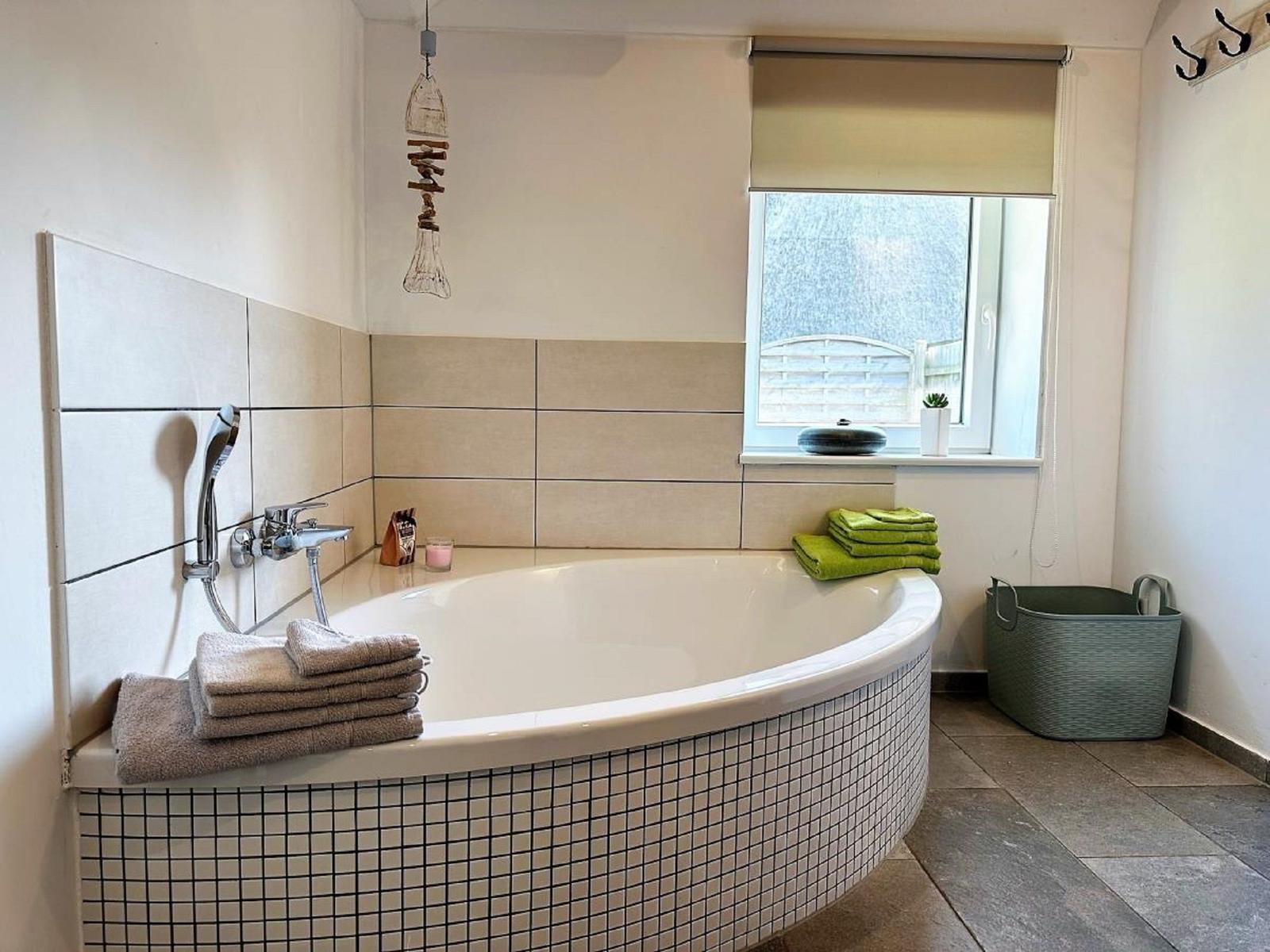 Bad mit Whirlpool, Fenster, Handtuch und Waschmaschinenkorb.