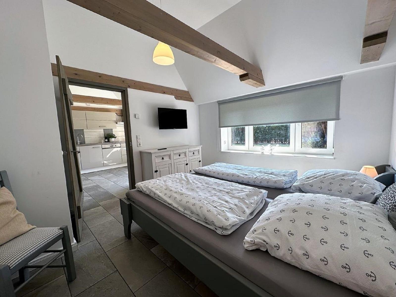 Schlafzimmer mit Doppelbett, Fenster und Blick in die Küche.