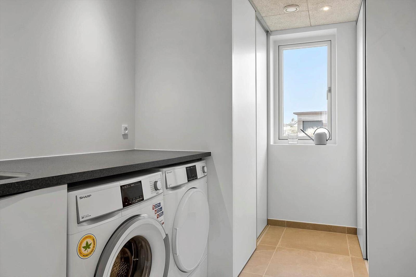 Waschmaschine und Trockner in einem hellen Raum mit Fenster.