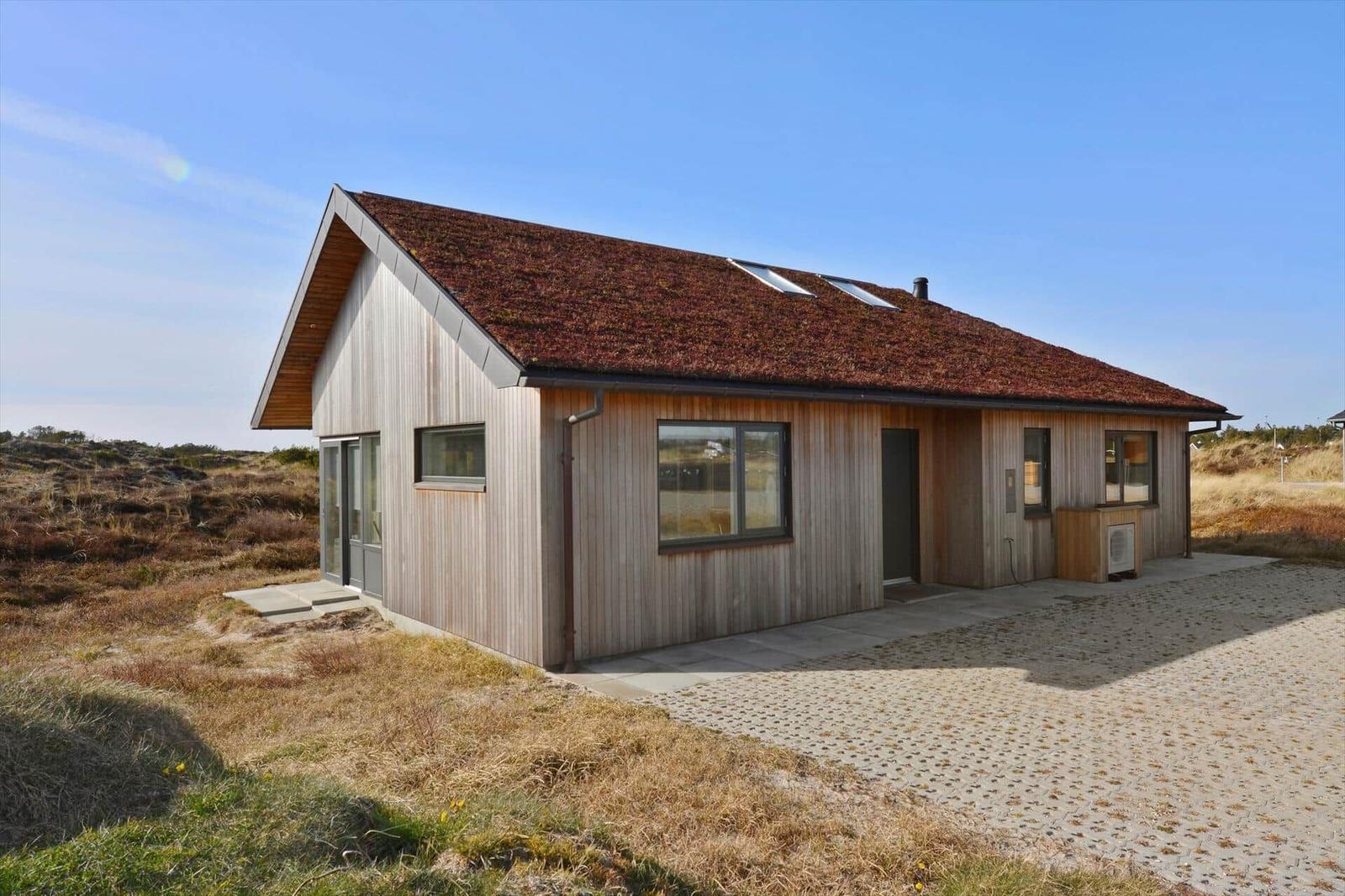 Moderne Holzhütte mit Dachgauben und großzügigem Außenbereich.