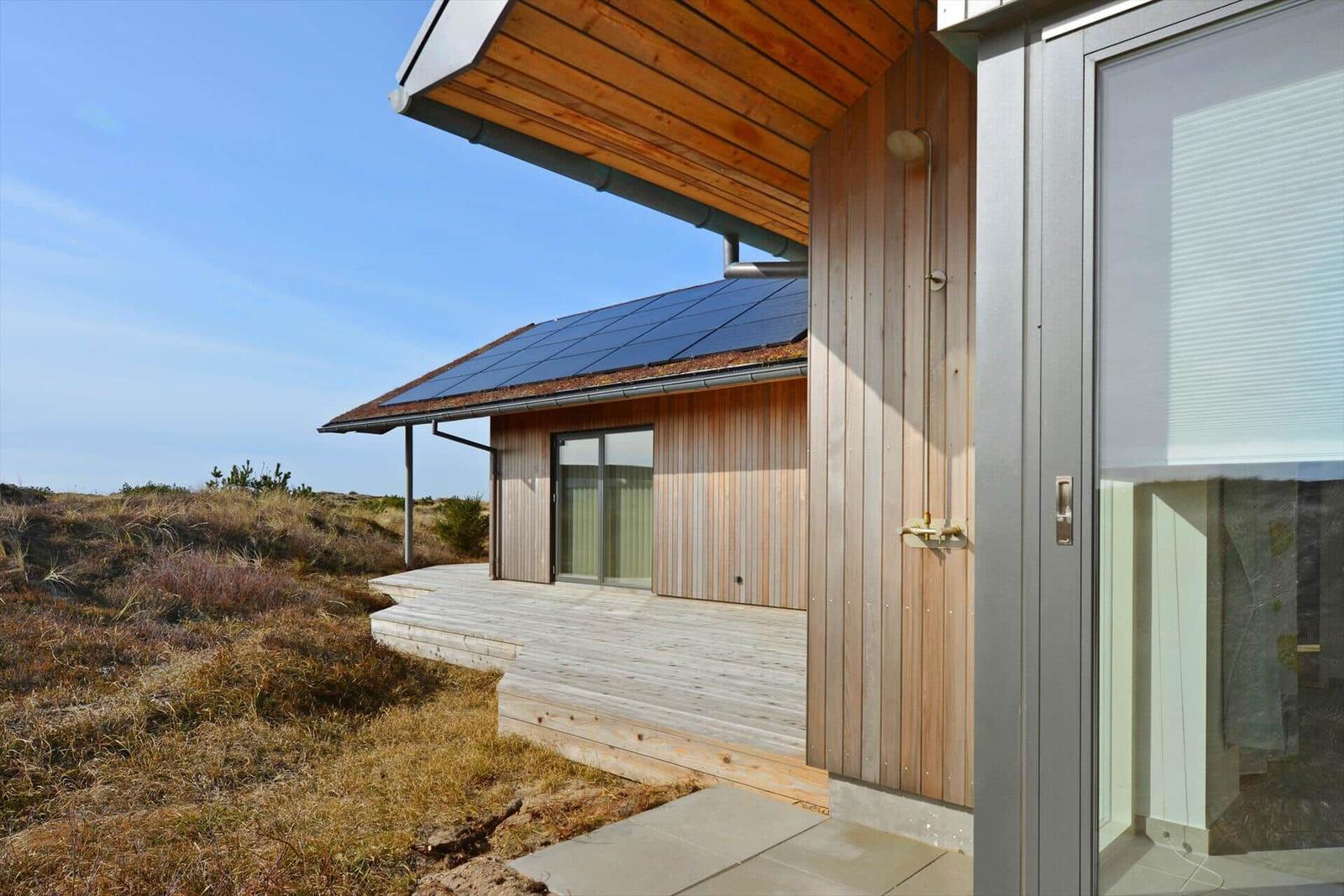Moderne Holzhütte mit Solarpaneelen und Terrasse im Freien