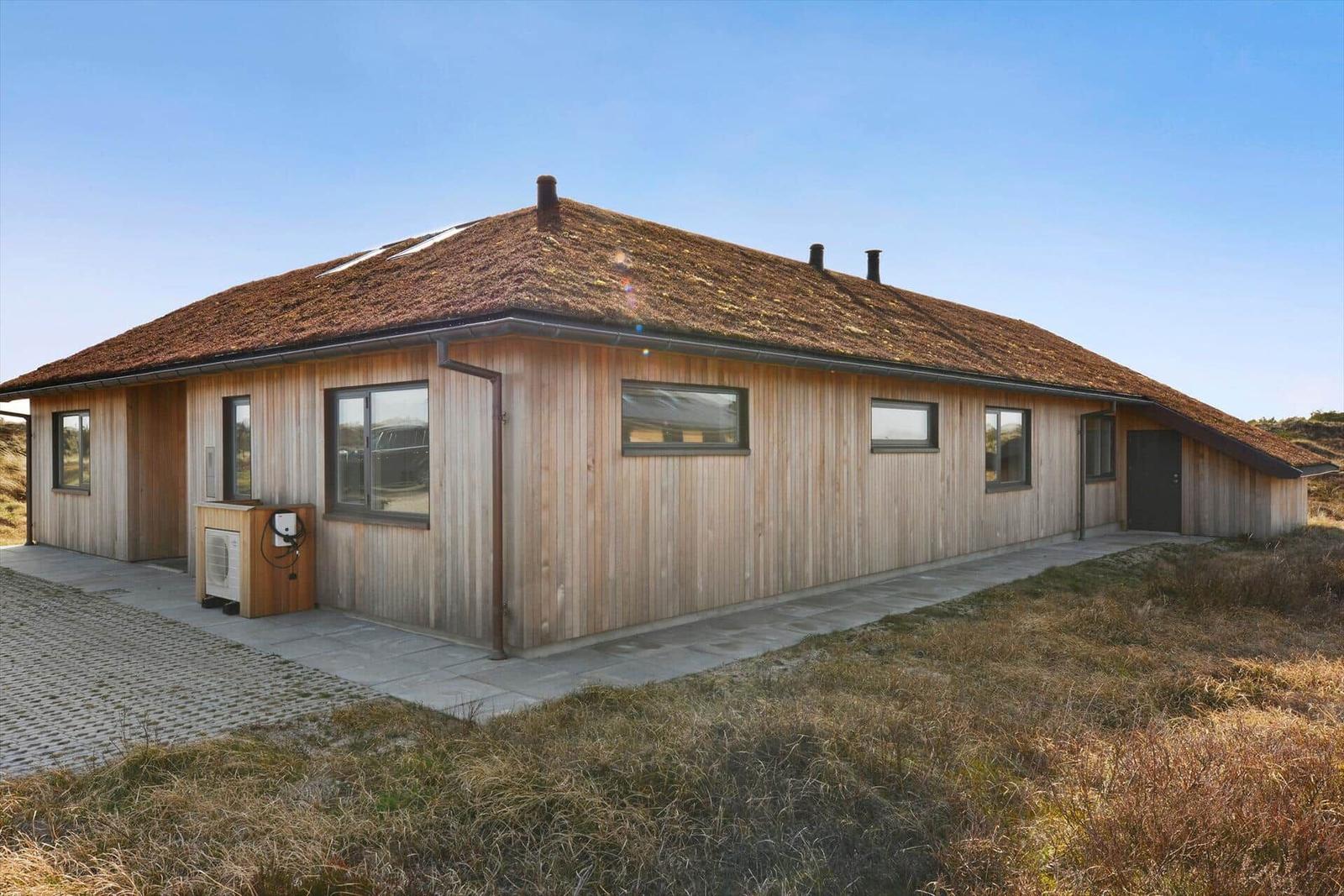 Holzhaus mit Dach aus Gras und mehreren Fenstern