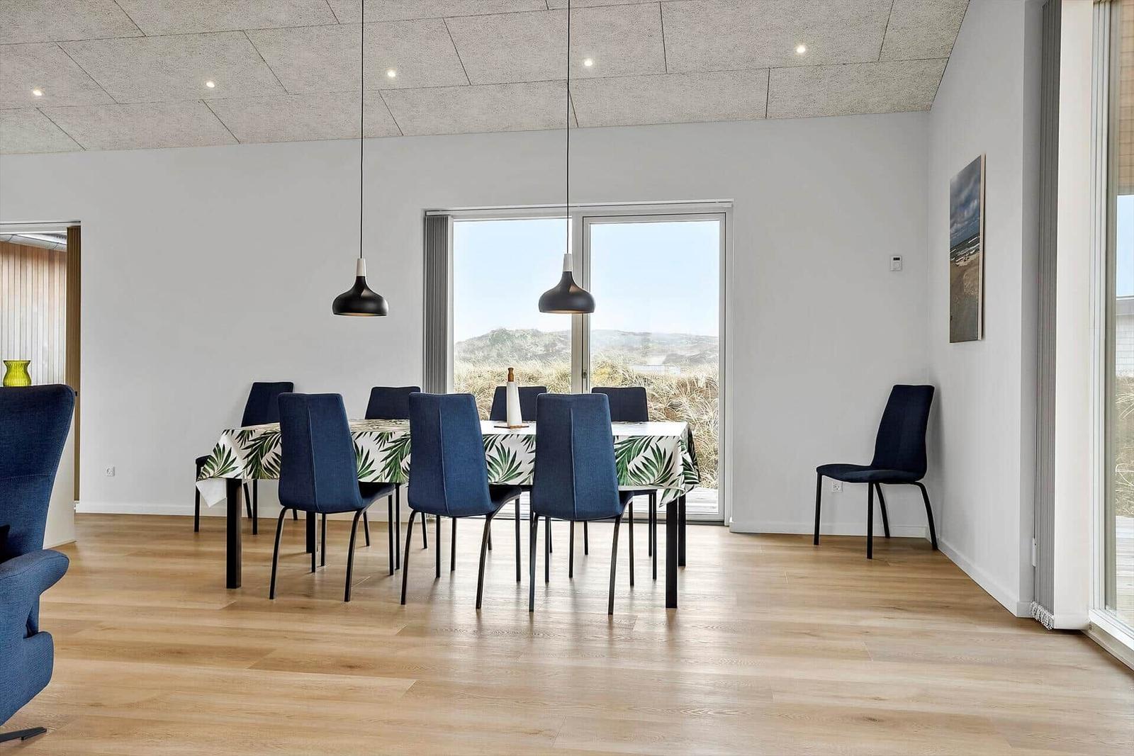 Esszimmer mit Tisch, Stühlen und Blick auf die Dünen.