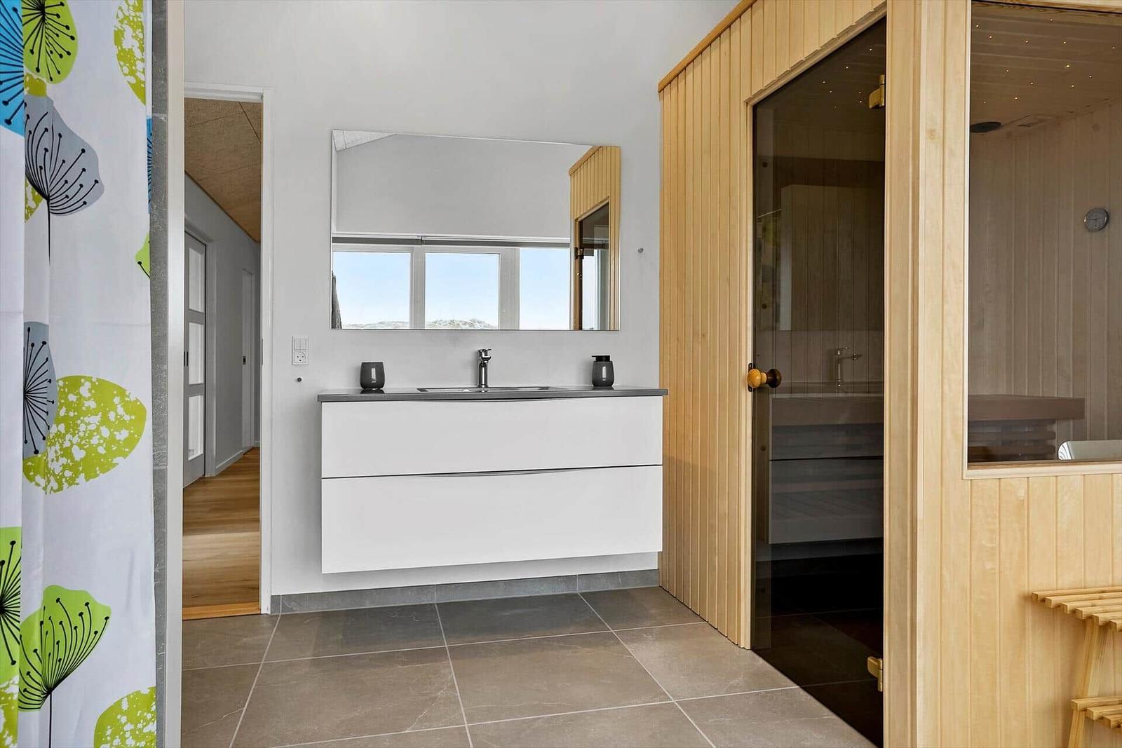 Badezimmer mit Waschbecken, Spiegel und Sauna