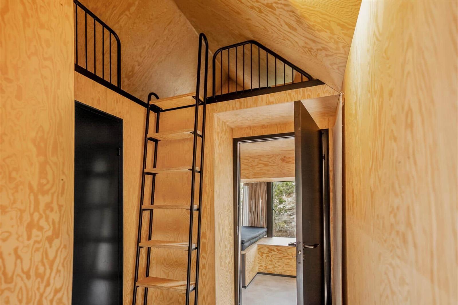 Holzvertäfelte Wohnung mit Doppelstockbett und Treppe.