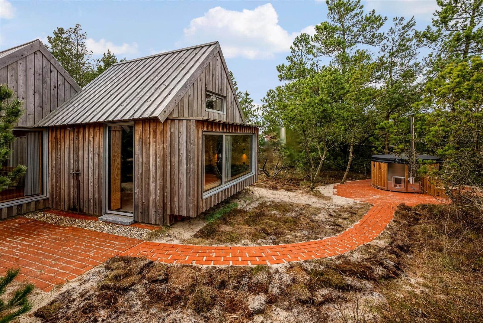 Holzhütte mit Glasfront und rotem Ziegelweg im Wald