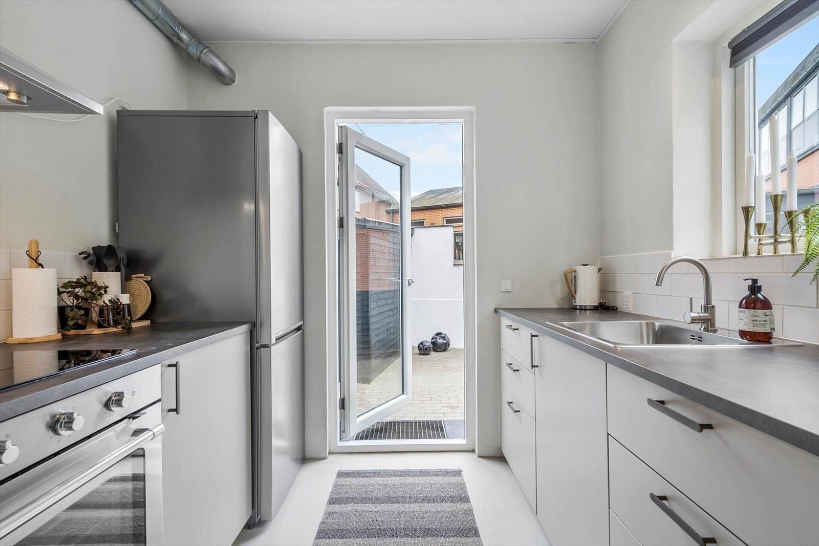 Küche mit Kühlschrank, Spüle und Tür zum Hof