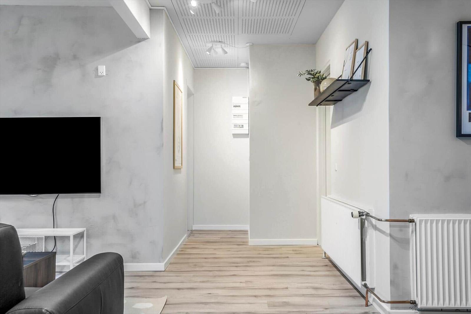 Flur mit Holzboden, Fernseher und Heizkörper an der Wand.