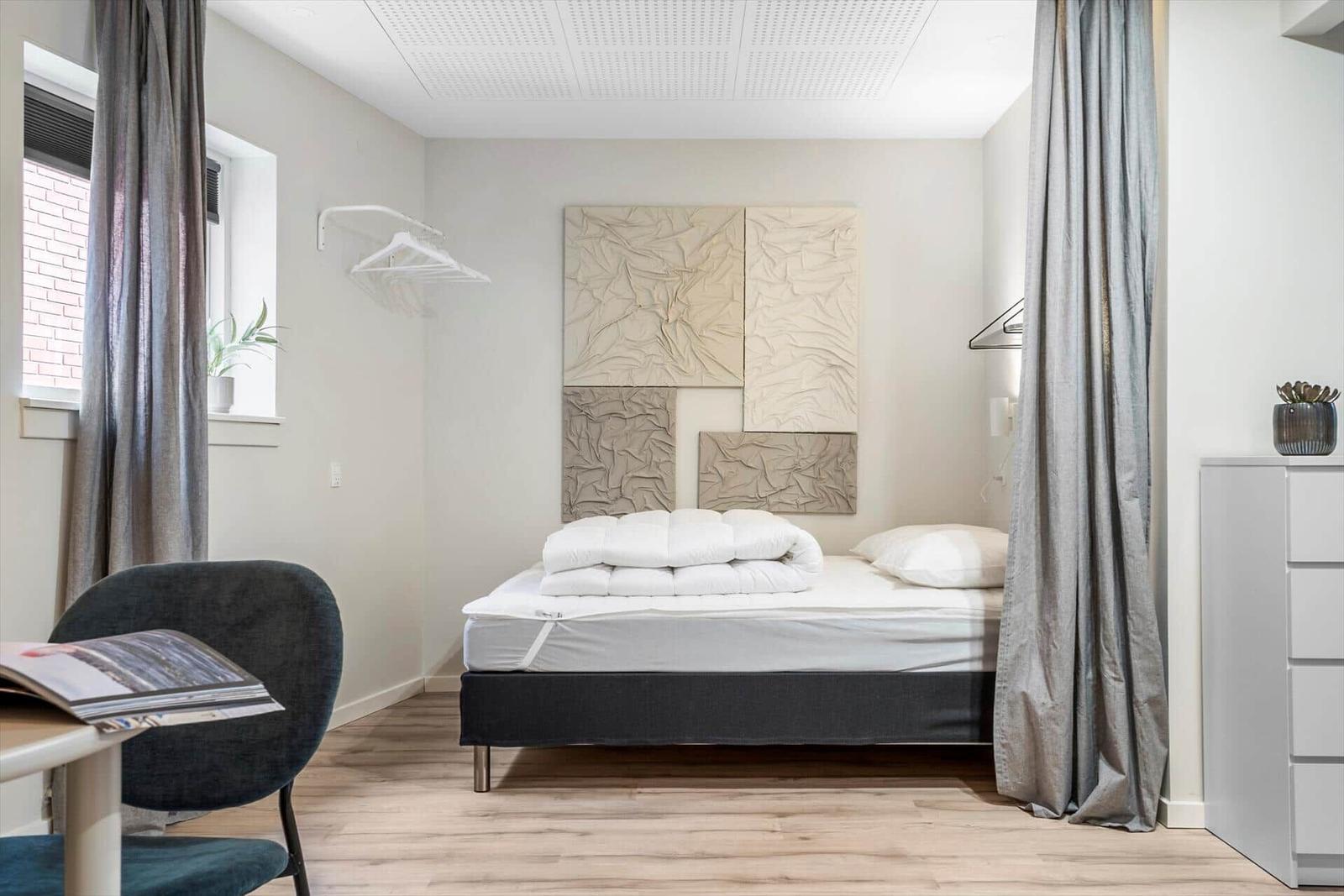 Schlafzimmer mit Bett, Vorhängen und Wanddekoration.
