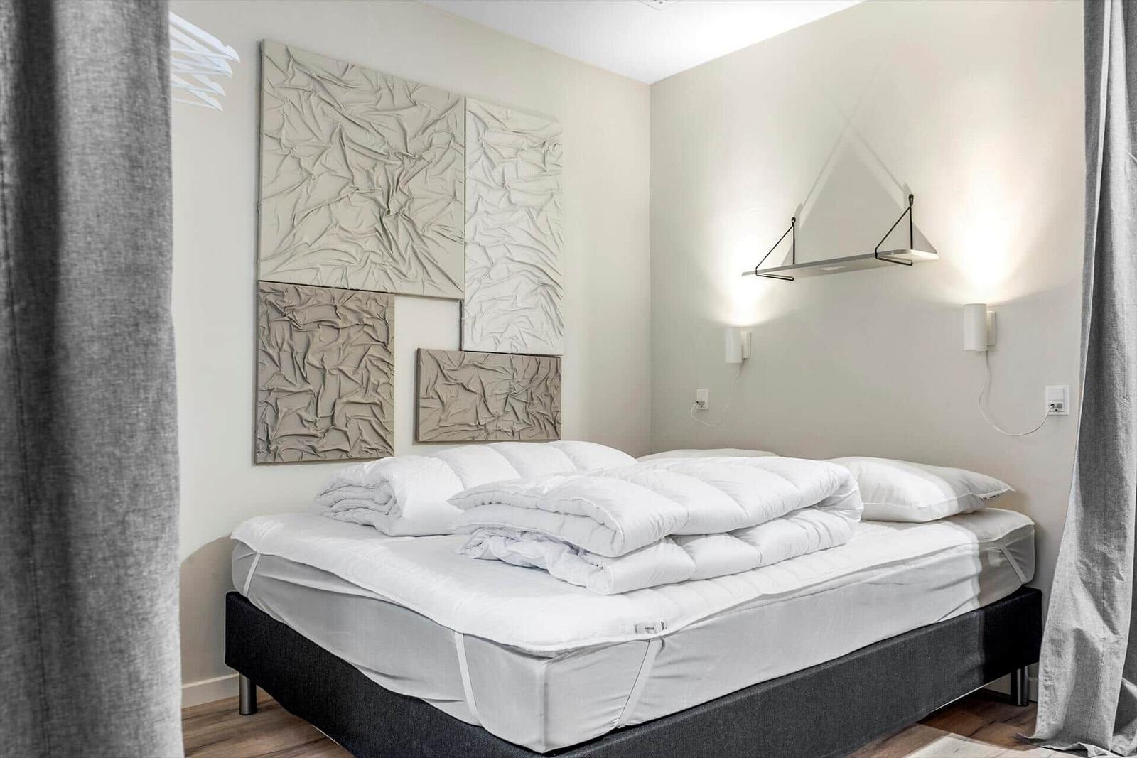 Schlafzimmer mit Bett, Wanddekoration und Wandlampe.