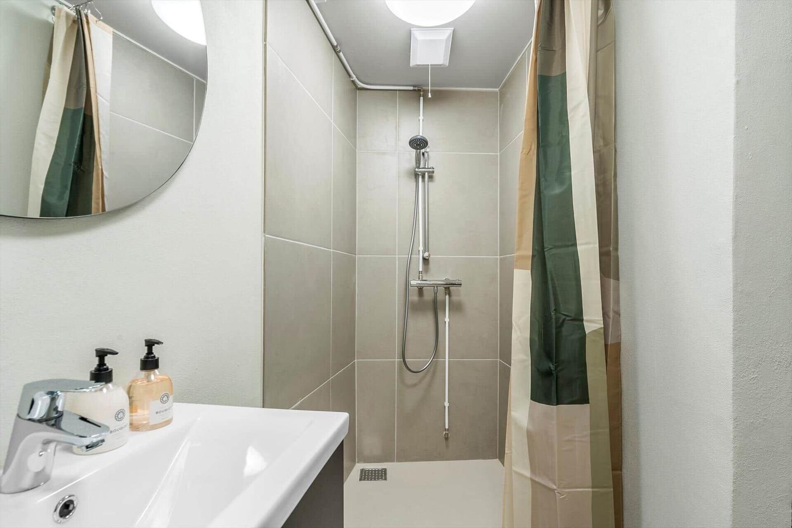 Badezimmer mit Dusche, Waschbecken und Spiegel