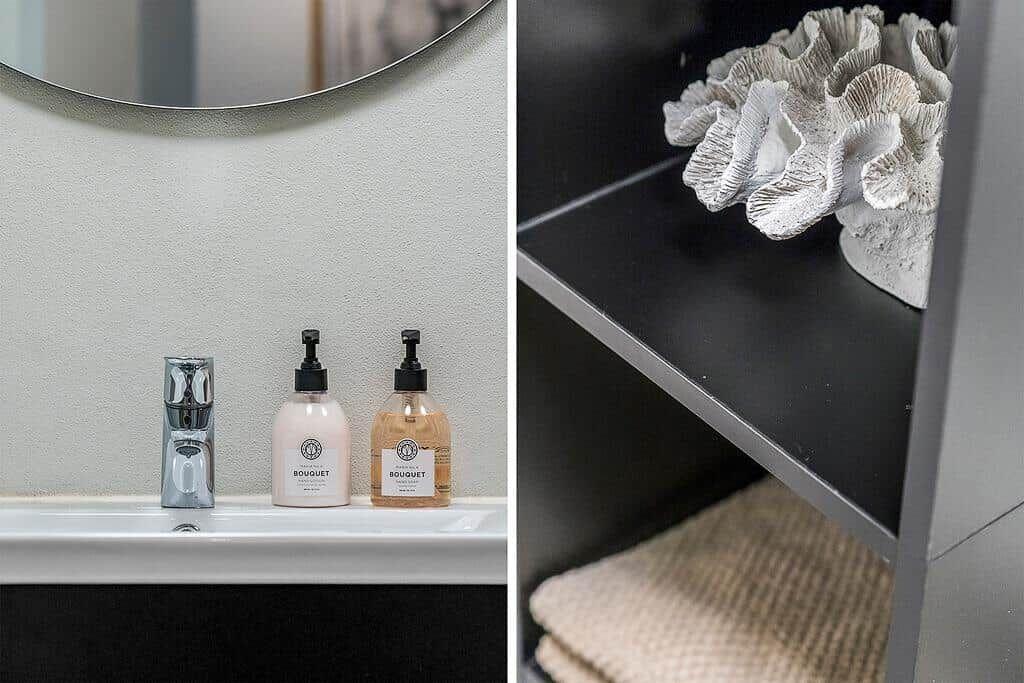 Waschbecken mit Wasserhahn und Seifenflaschen. Regal mit Korallen-Dekoration und Handtuch.