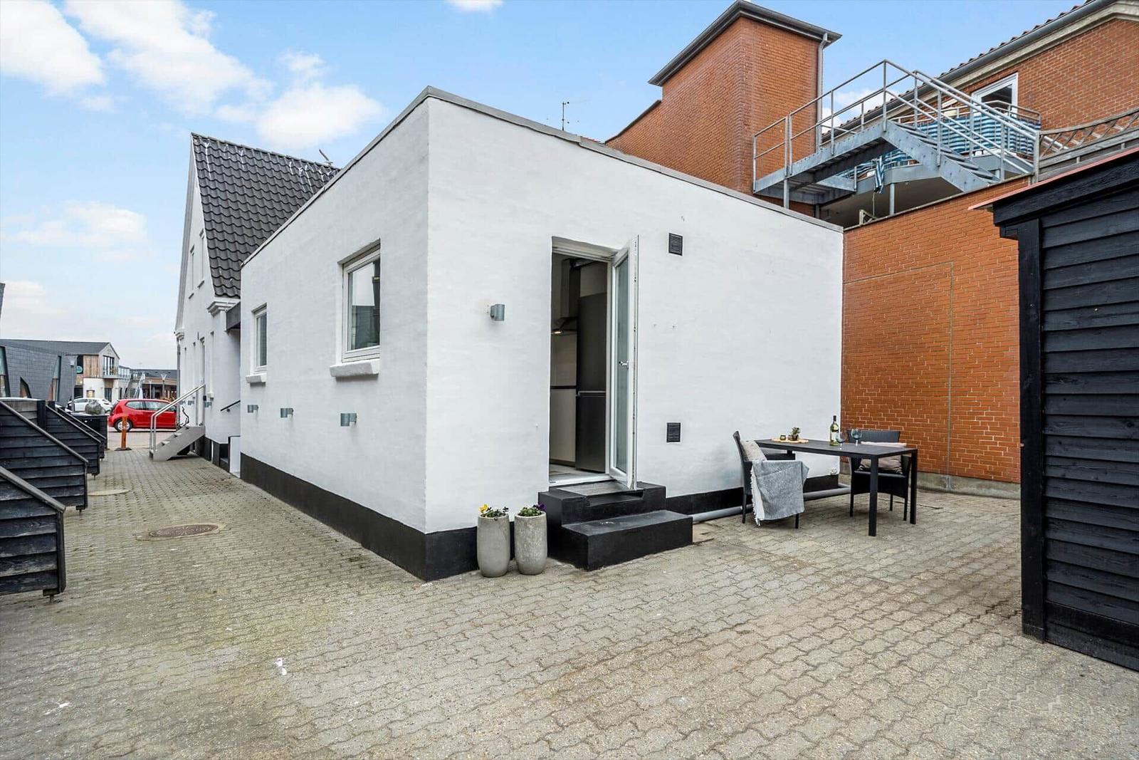 Moderne weiße Hütte mit Terrasse und Essbereich im Außenbereich.