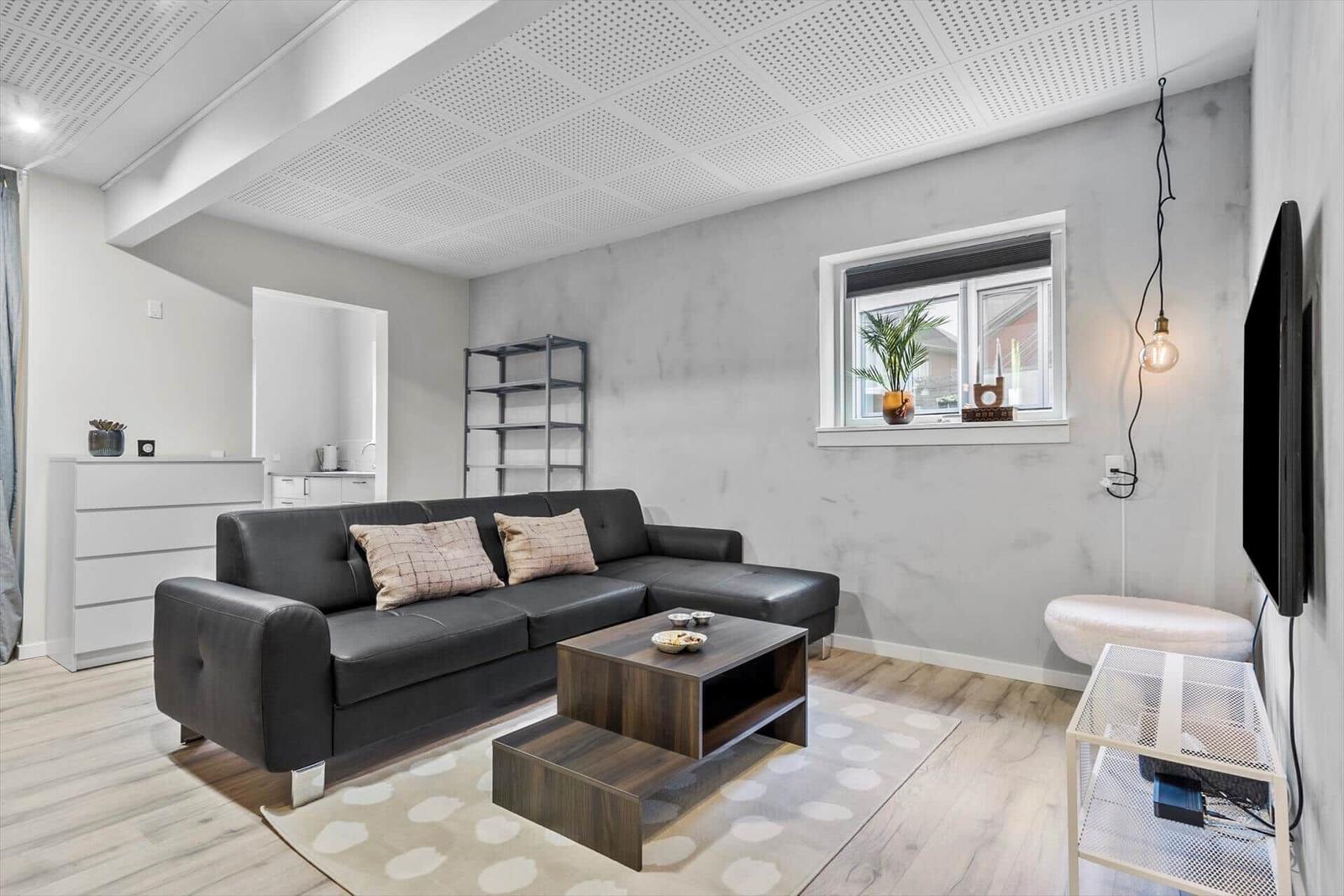 Wohnzimmer mit grauem Sofa, Holztisch und Wandbild