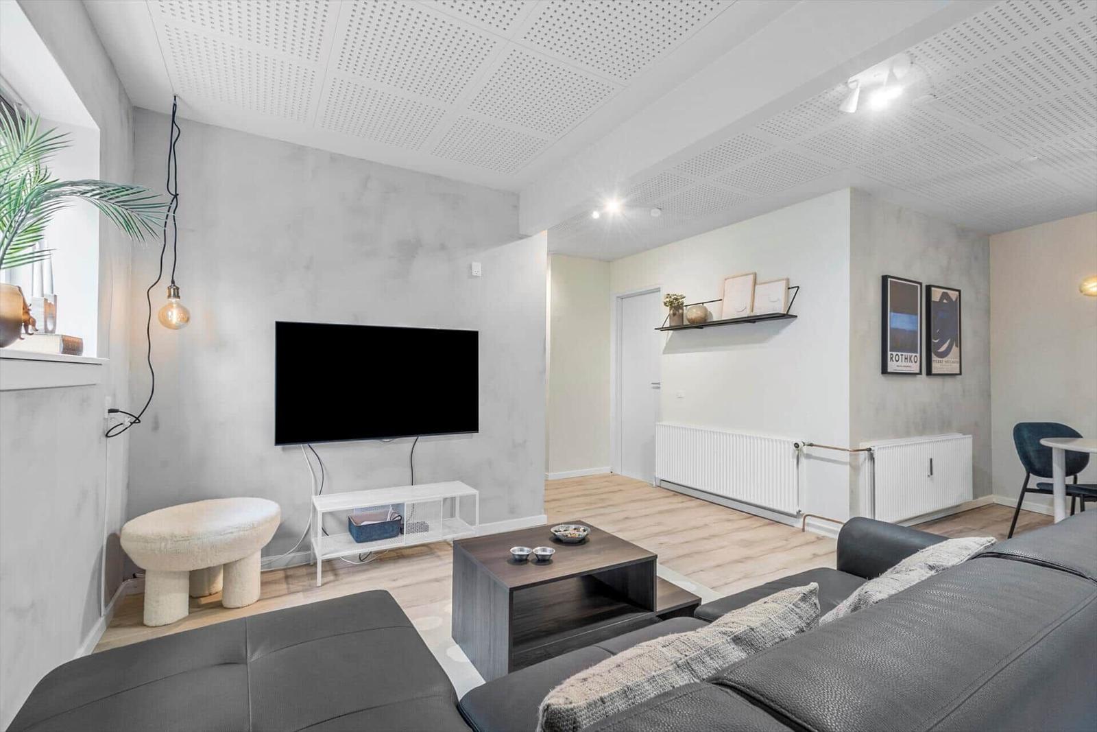 Wohnzimmer mit Sofa, Fernseher und Couchtisch.