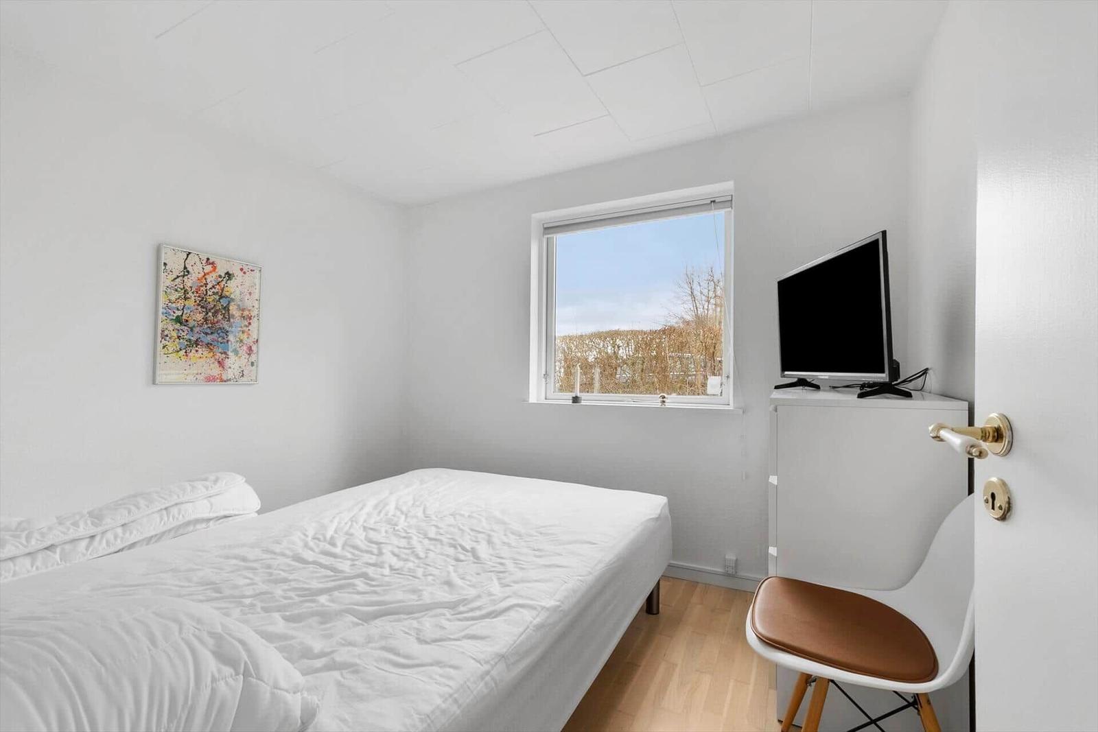 Schlafzimmer mit Bett, Fernseher und Fenster
