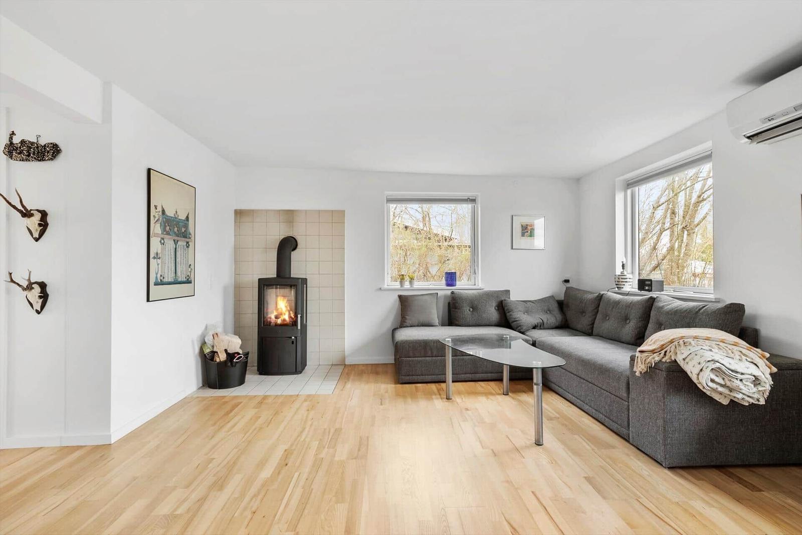 Wohnzimmer mit Kamin, grauem Sofa und Holzboden.