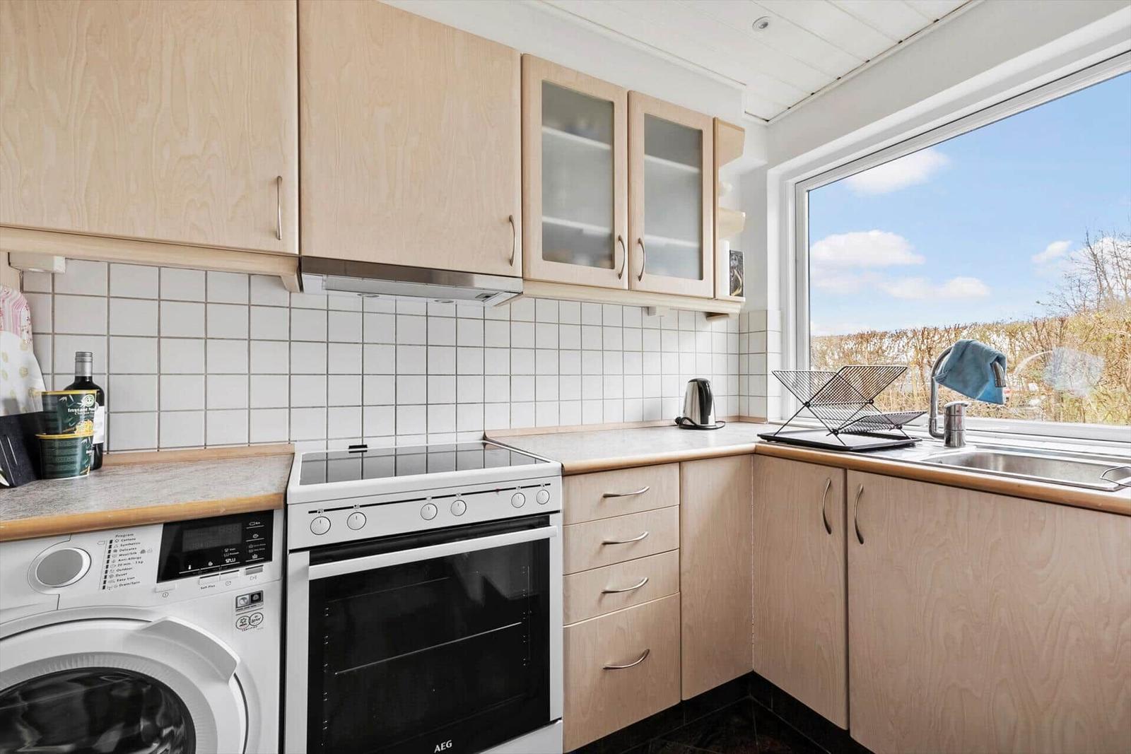 Küche mit Holzschränken, Spüle und Fensterblick