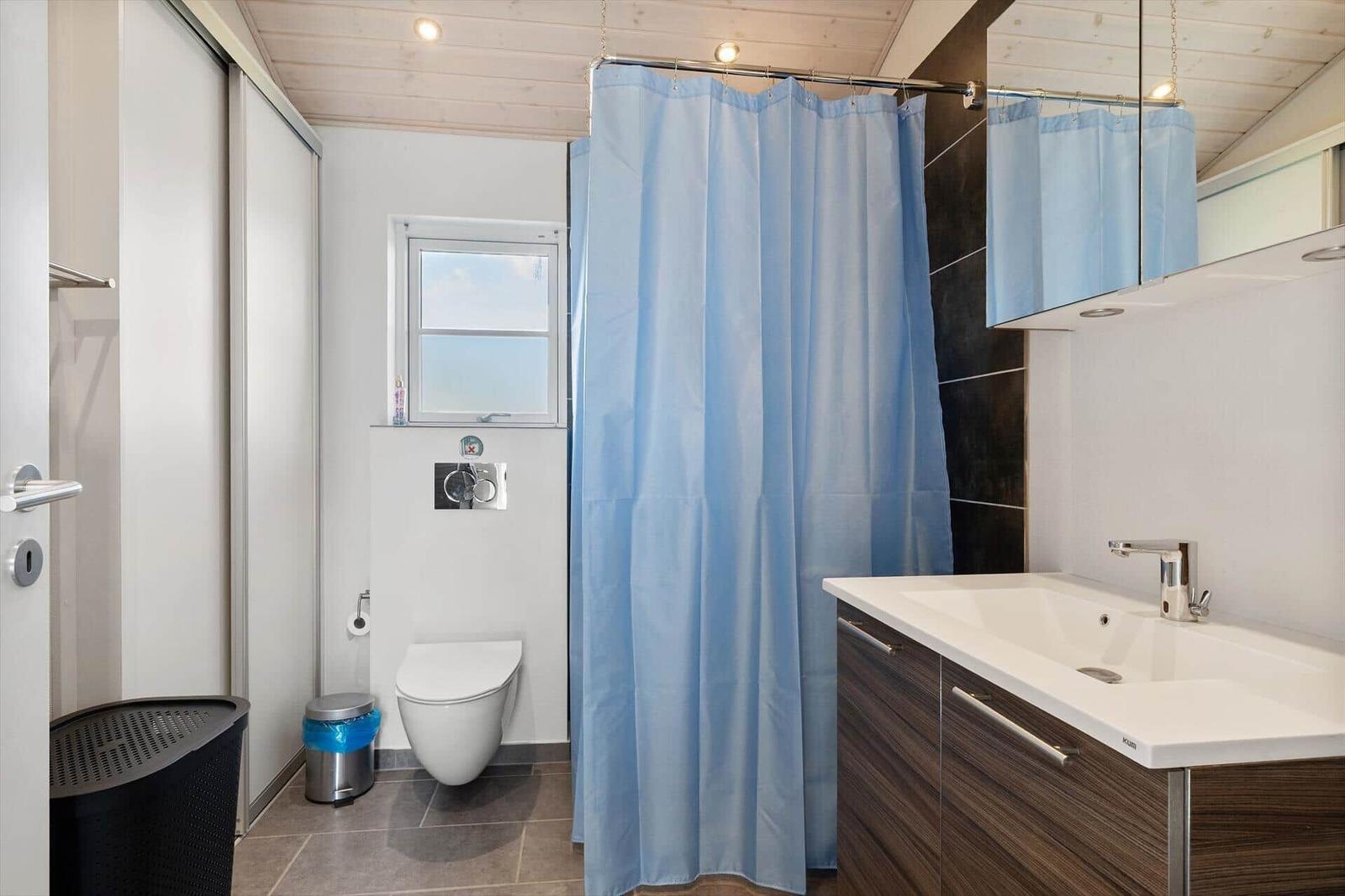 Badezimmer mit Dusche, Waschbecken und Toilette.