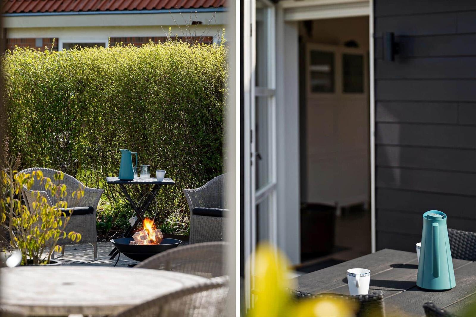 Terrasse mit Sitzgelegenheiten und Feuerkorb. Tisch mit Kanne und Tassen.