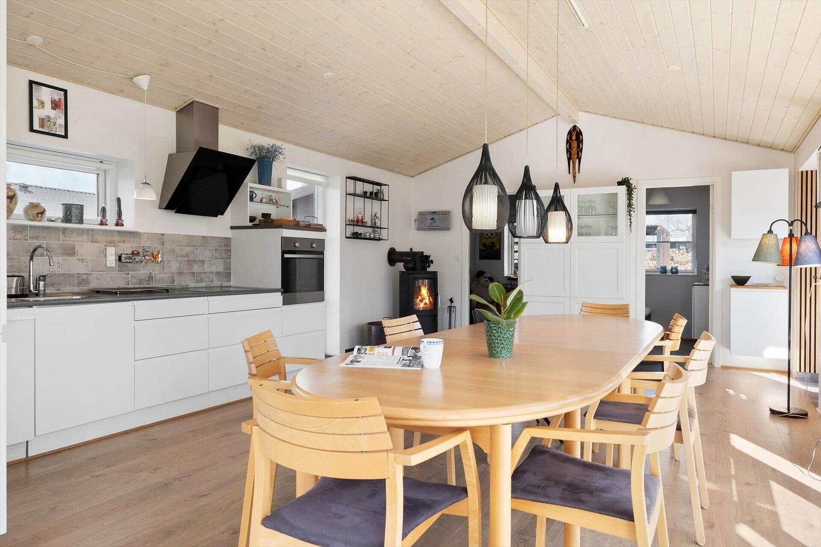 Küche mit Essbereich und Holztisch. Kamin und moderne Beleuchtung.