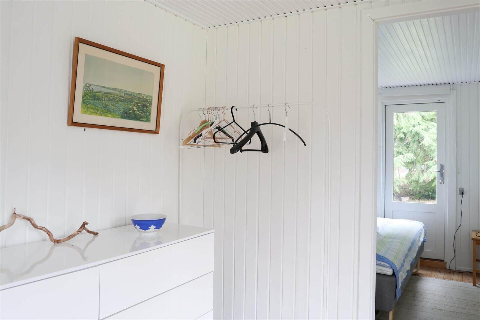 Schlafzimmer mit Kleiderständer, Schrank und Fenster zum Garten.