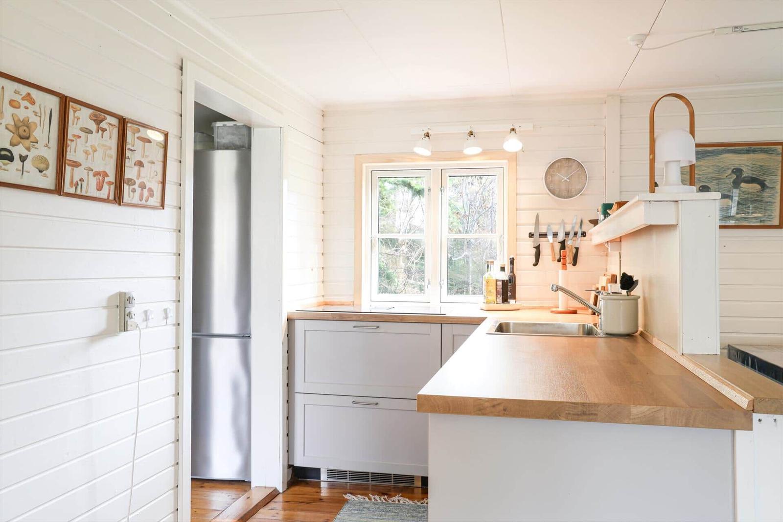 Küche mit Holz Arbeitsplatte, Kühlschrank und Fenster mit Blick auf Außenterrasse.