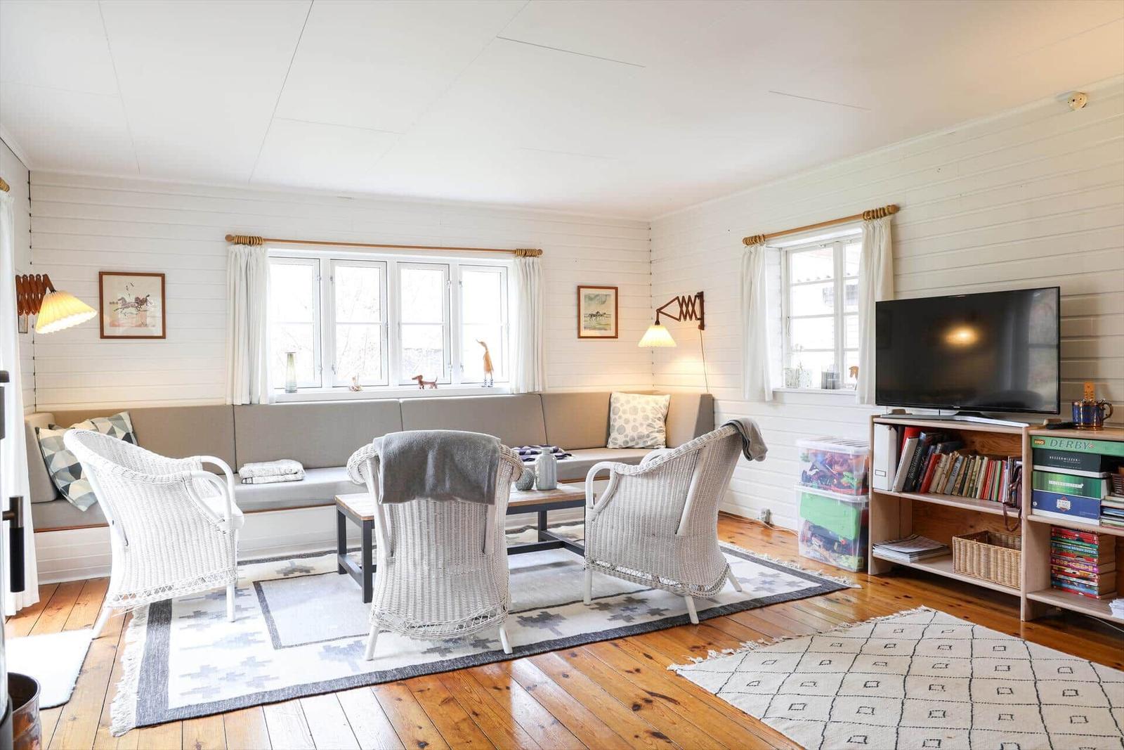 Wohnzimmer mit Sofa, Stühlen, Fernseher und Bücherregal.