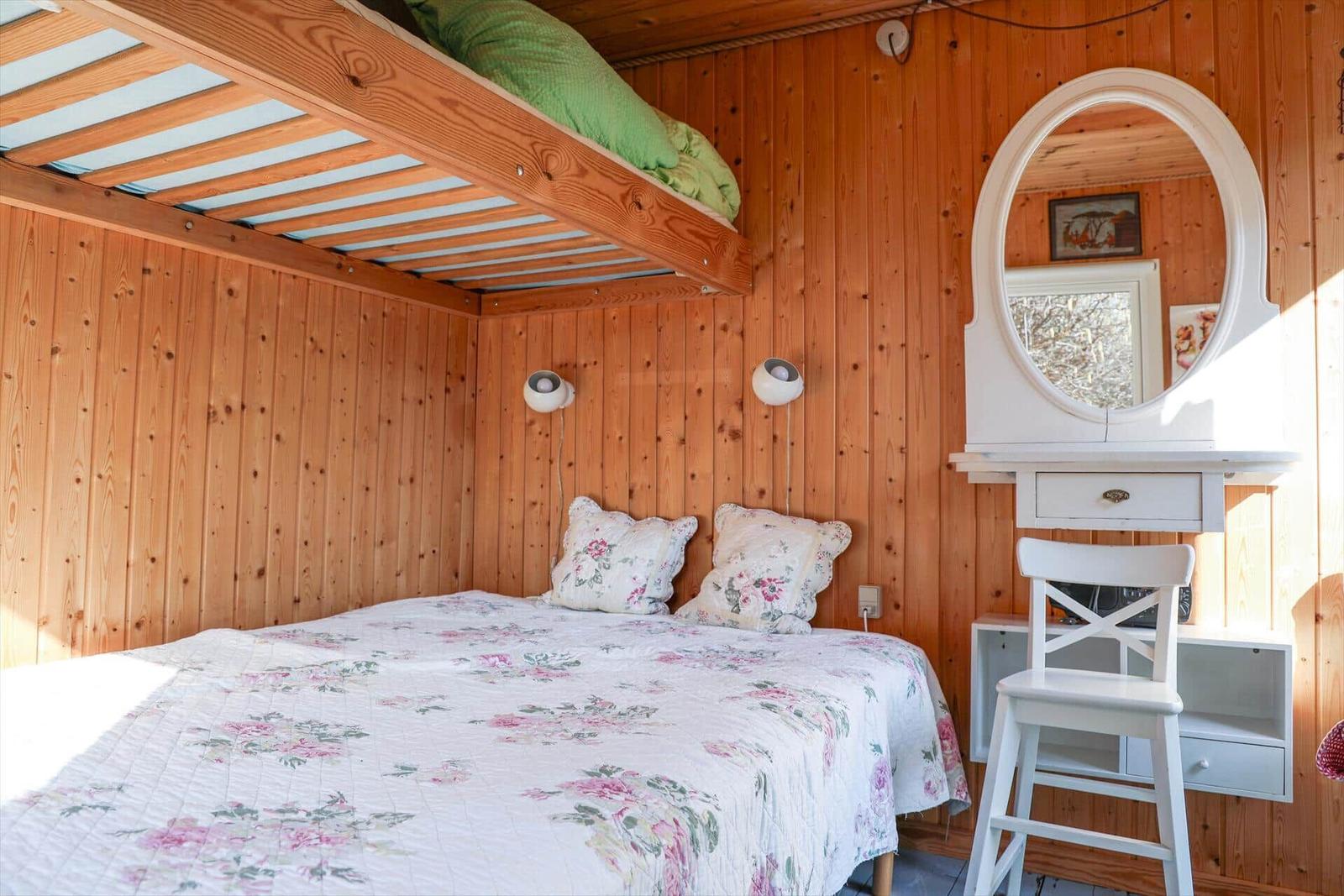 Zimmer mit Doppelbett, Hochbett und weißem Schminktisch mit Spiegel.