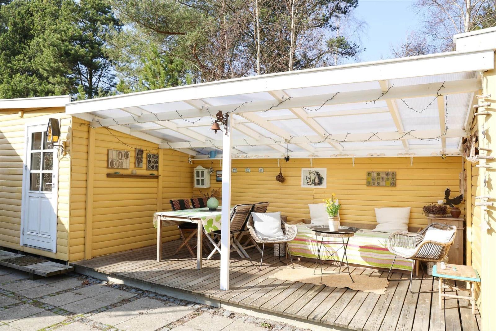 Terrasse mit Sitzgelegenheiten und Tisch unter einer weißen Markise.