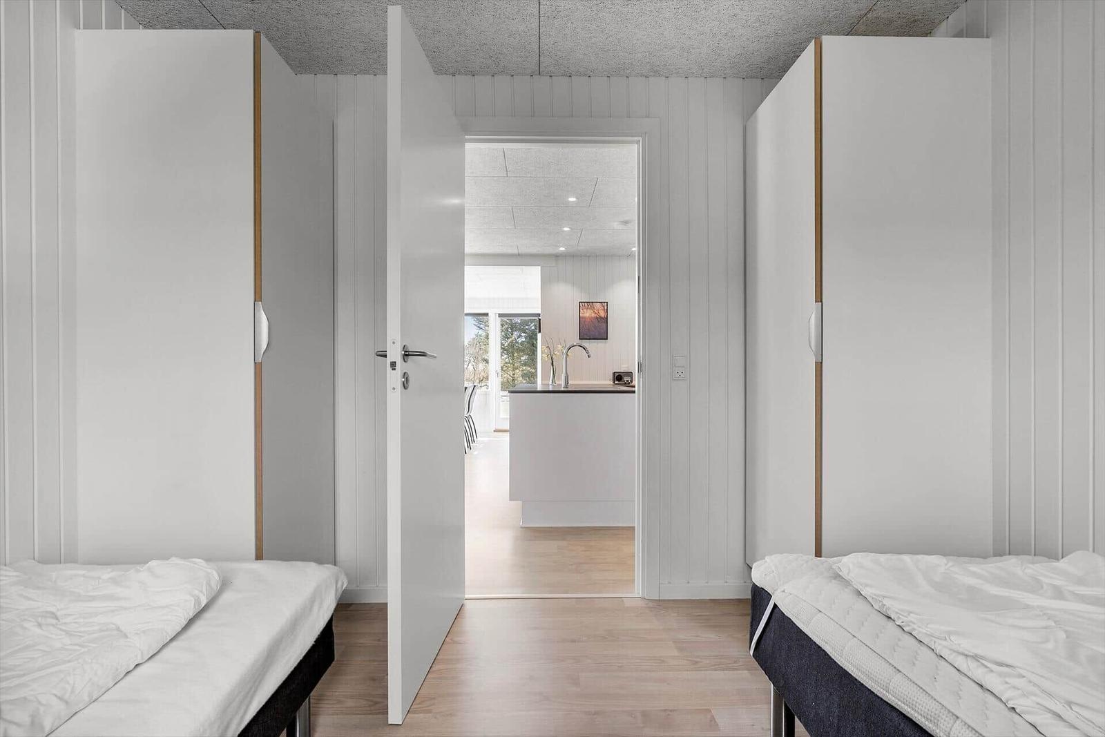 Zwei Schlafzimmer mit Betten und Schränken. Durchgang zur Küche mit Arbeitsplatte.