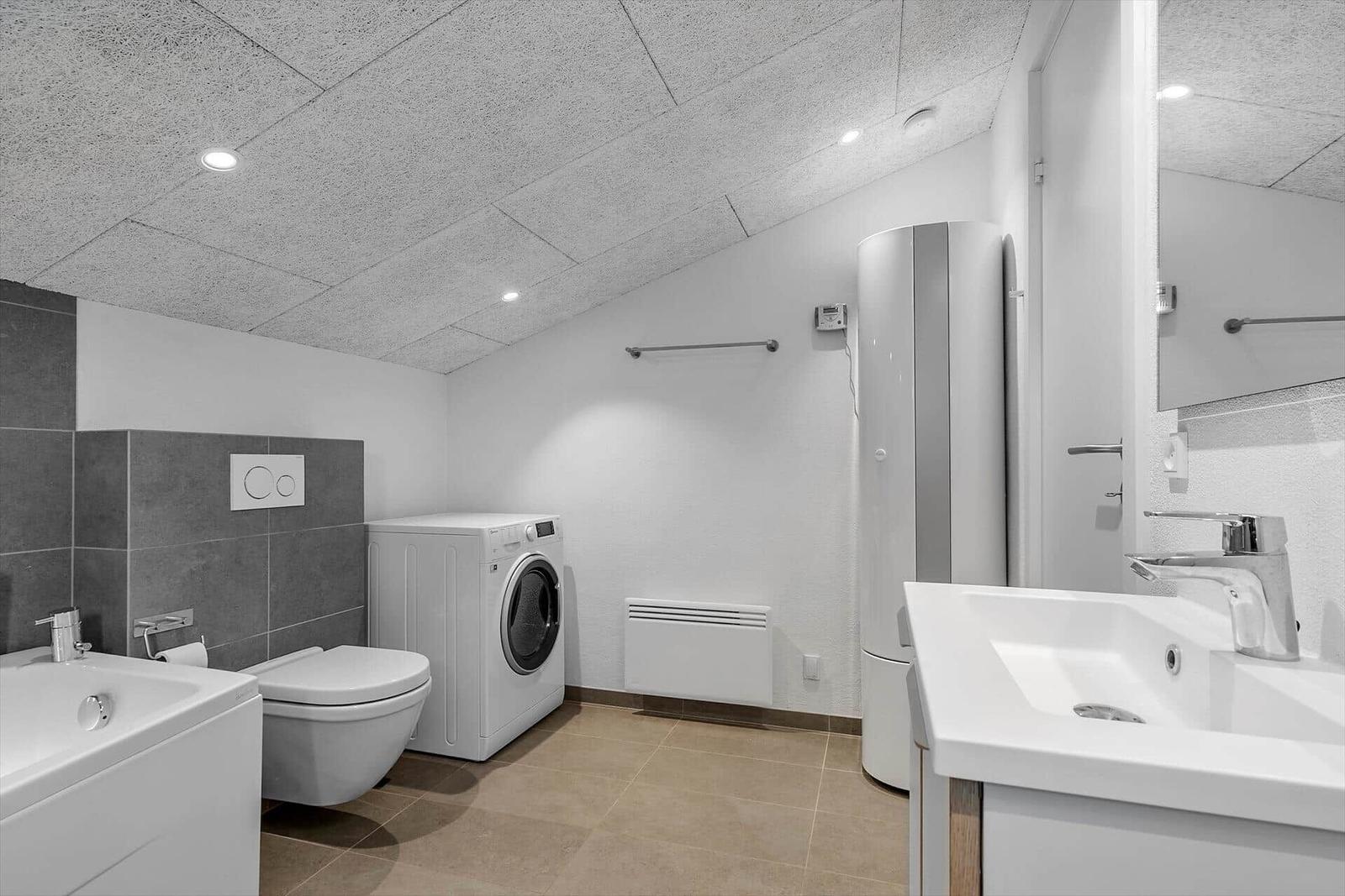 Badezimmer mit Waschmaschine, Dusche und Waschbecken.