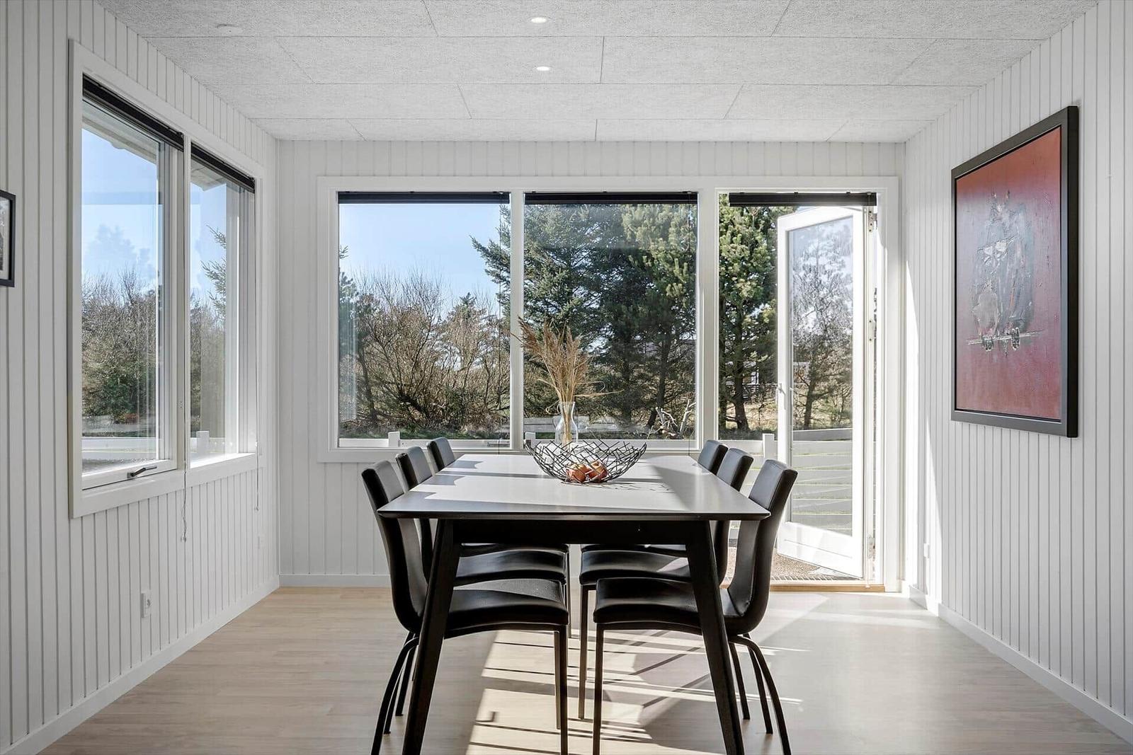Esszimmer mit Tisch, Stühlen und Fenstern zur Außenseite.