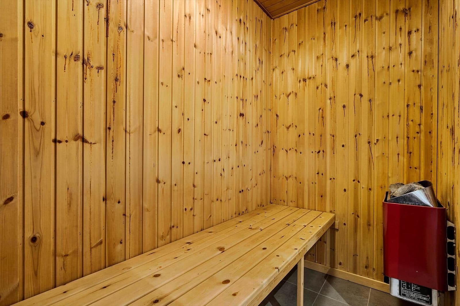 Sauna mit Holzwand und Bank. Heizung rechts.