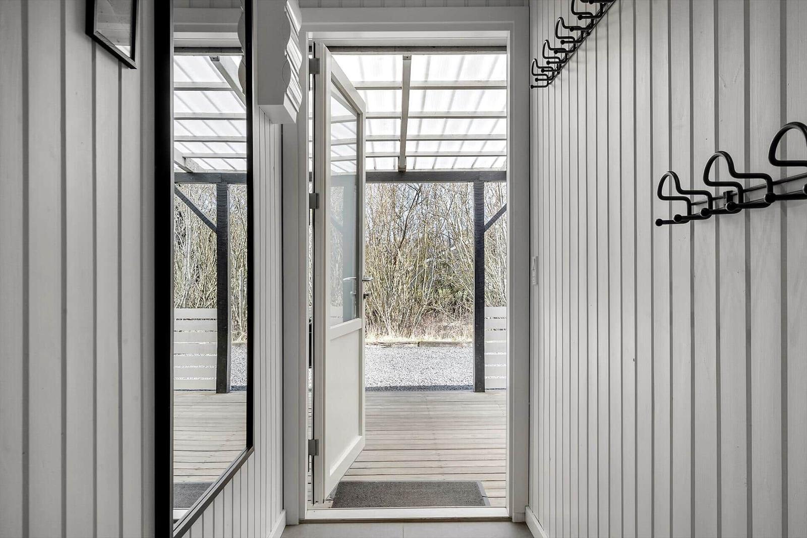 Haus mit offener Tür zum Außenbereich mit Holzdecke und Bäumen