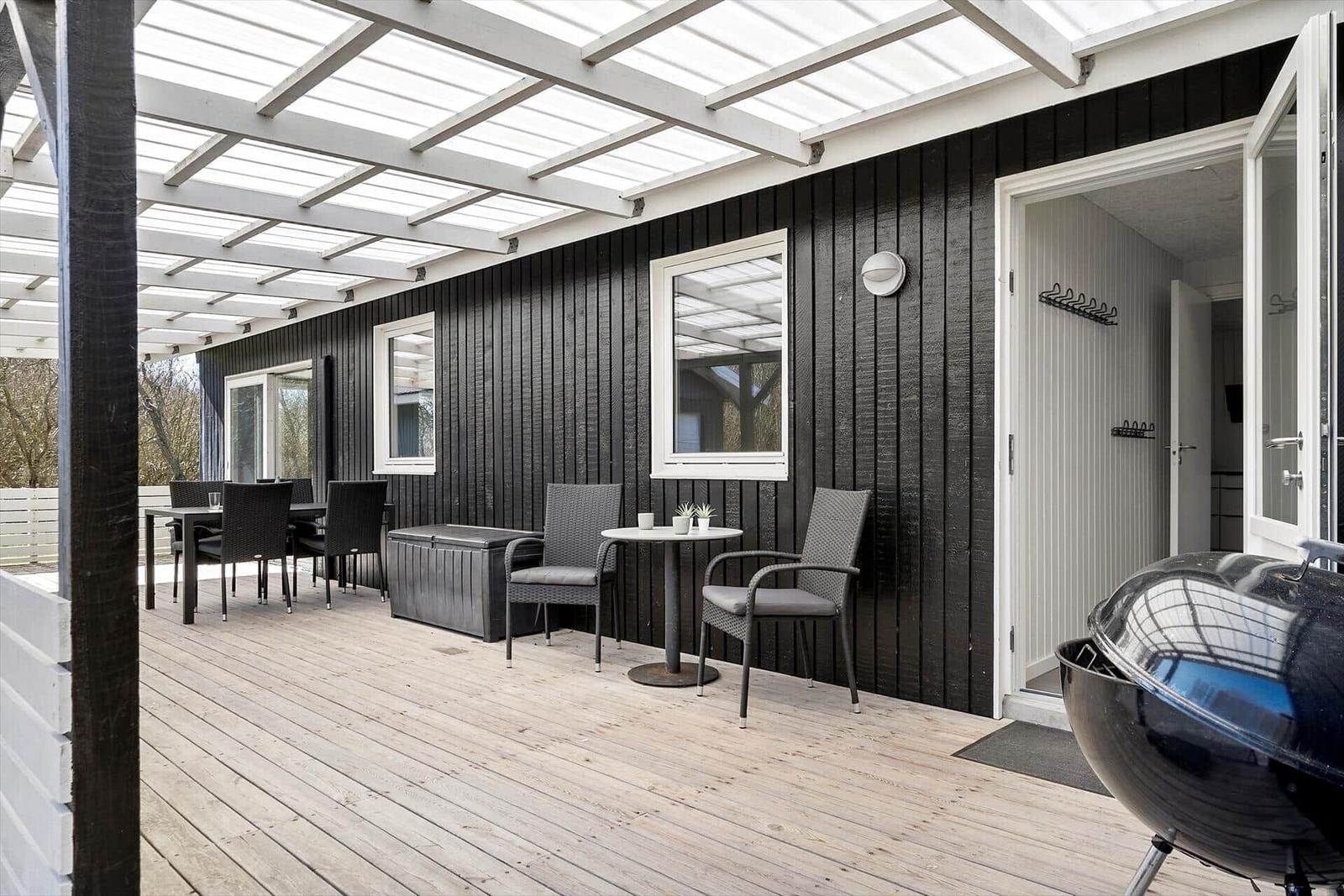 Terrasse mit Sitzgelegenheiten und Grill unter Glasdach
