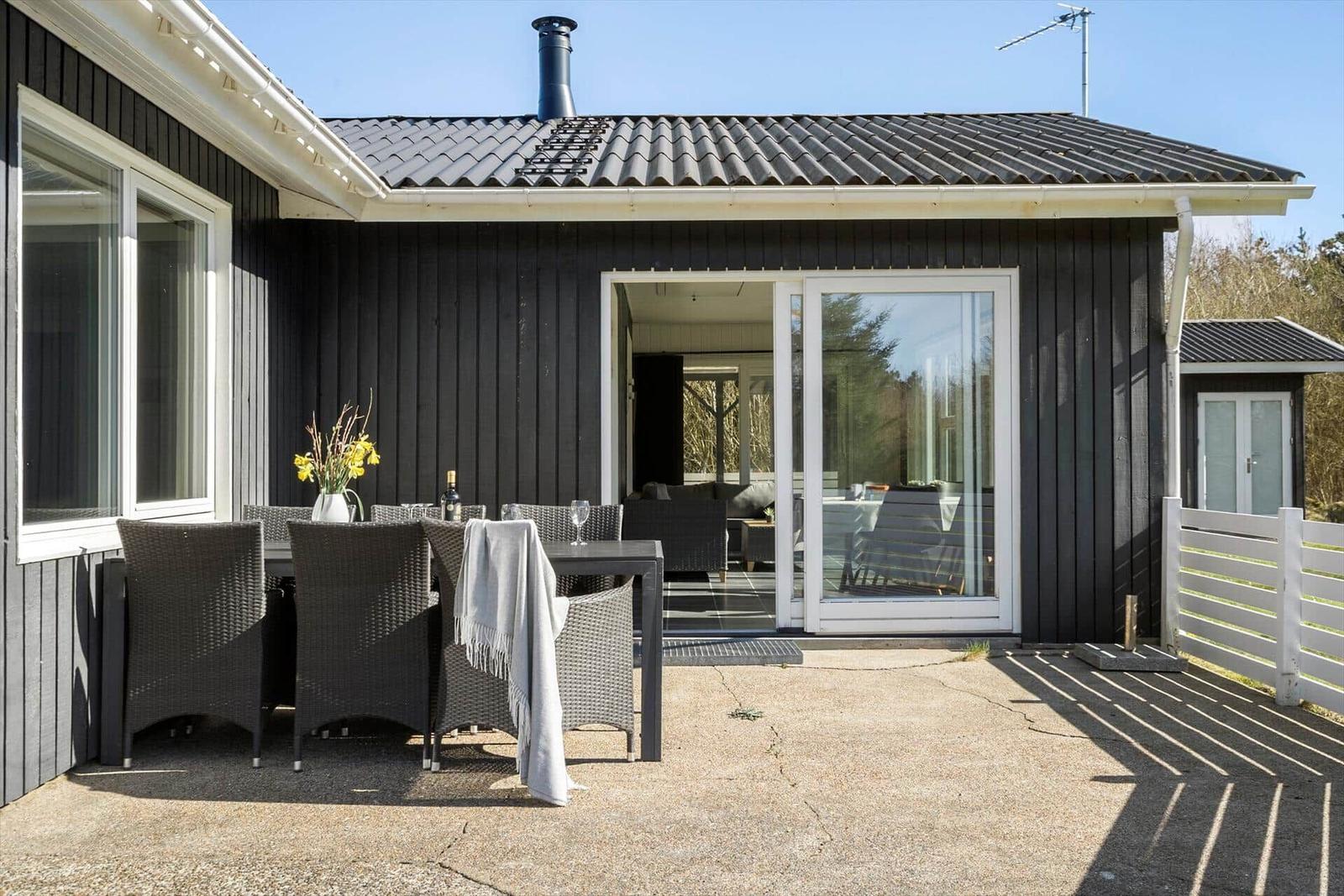 Haus mit Terrasse, Sitzgruppe und Glastüren zum Innenraum.
