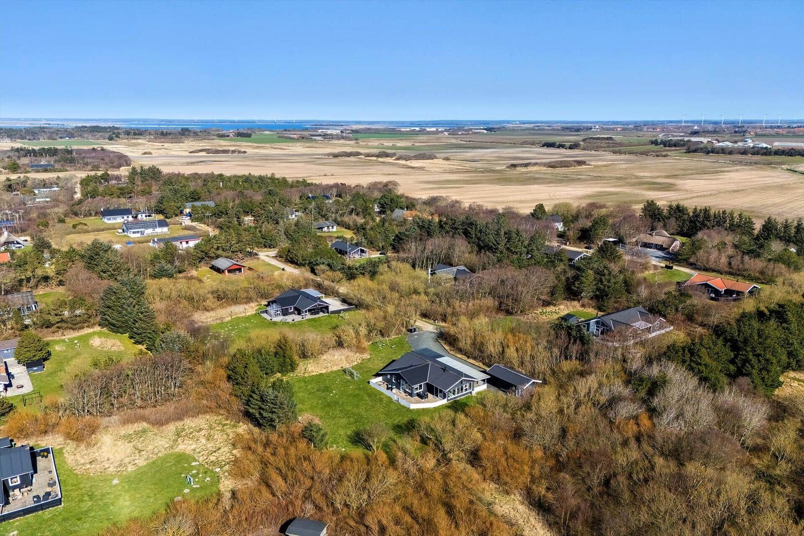 Luftbild von Ferienhäusern in einer ländlichen Umgebung mit Feldern und Wald.